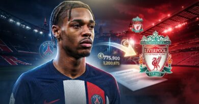 صورة مركبة واقعية ومليئة بالدراما (HDR) للاعب كرة القدم الشاب برادلي باركولا، وهو يرتدي قميص باريس سان جيرمان ويعبر عن خيبة الأمل وعدم اليقين، وينظر إلى الجانب نحو شعار ليفربول
