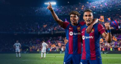 An ultra-realistic, cinematic sports photograph capturing FC Barcelona players Raphinha and Lamine Yamal celebrating intensely after a goal at a packed Camp Nou stadium at night, with the left side of the frame reserved for a headline.