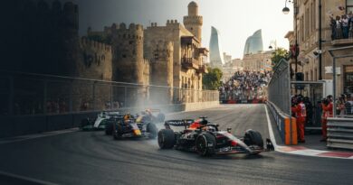 A high-speed, ultra-photorealistic Formula 1 sports journalism photograph capturing single-seater cars racing through the historic streets of the Baku City Circuit during the Azerbaijan Grand Prix, featuring ancient stone walls and modern skyscrapers in the background, with clean negative space in the upper-left.
